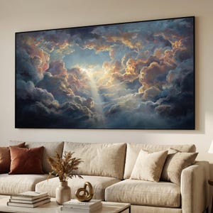 May include: Large framed artwork depicting a dramatic sky scene. The painting features a vibrant display of clouds in shades of blue, gold, and pink, with a bright light shining through. The artwork is displayed above a beige sofa.