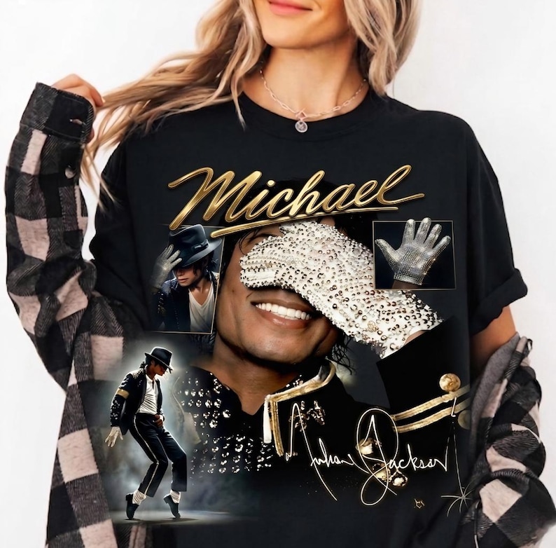 May include: Black t-shirt featuring a collage of images of Michael Jackson, including a portrait, a glove, and a dancing pose. The word "Michael" is written in gold script above the images, with the signature below.