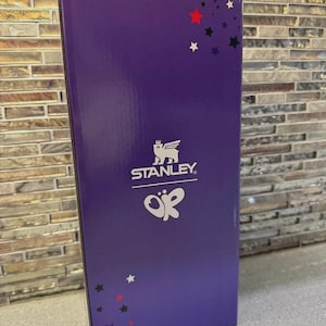 May include: A purple box with the Stanley logo and the letters "OK" in white. The box has a glossy finish and is decorated with red, black, and white stars. The box is rectangular and stands upright.