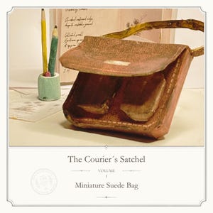 May include: A miniature brown suede satchel with a flap closure and a handle, accompanied by a small light green pencil holder containing two pencils, and a book with handwritten text titled The Courier's Satchel Volume 1 Miniature Suede Bag.