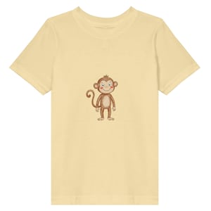 Könnte beinhalten: Ein hellgelbes T-Shirt mit einer Cartoon-Affen-Illustration. Der Affe ist braun mit einem lächelnden Gesicht und einem eingerollten Schwanz. Das T-Shirt besteht aus einem weichen Material.