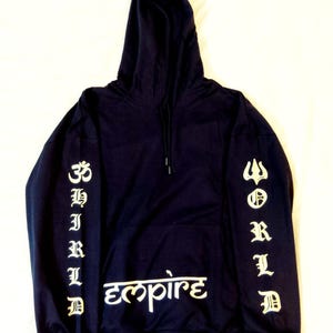 Op de afbeelding: Marineblauwe hoodie met witte letters. De linkermouw toont het woord "CHILD" verticaal, en de rechter mouw zegt "WORLD". Het woord "Empire" staat in een gestileerd lettertype op de borst.