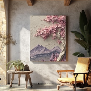 May include: A textured wall art piece featuring a serene landscape. The artwork depicts a blossoming tree with pink flowers, a mountain range, and a neutral background. The piece is displayed in a well-lit, rustic-style room.