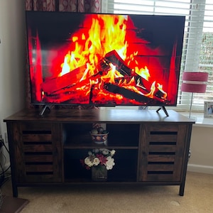 May include: A white ceramic mug with a black handle and the text "But First, Coffee" in a bold, black font. The mug is set against a blurred background, suggesting a cozy setting.