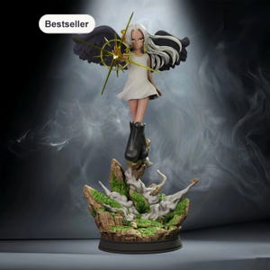 Puede incluir: Una figura coleccionable con cabello largo blanco, alas negras y vestido blanco, sosteniendo un emblema dorado en forma de estrella. La figura se alza sobre una base rocosa con musgo verde y efectos de humo. Etiqueta Bestseller visible.