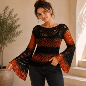 Könnte beinhalten: Ein langärmeliges Häkeloberteil mit einem offenmaschigen Strickmuster und einem Farbverlauf von Schwarz an den Schultern und in der Mitte bis zu einem tiefen gebrannten Orange an den ausgestellten Glockenärmeln und dem unteren Saum, über einem schwarzen Unterteil.