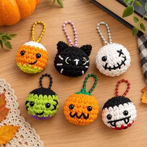 Puede incluir: Seis llaveros redondos de ganchillo con temática de Halloween y cadenas de bolas. Los diseños incluyen un caramelo de maíz, un gato negro, un fantasma blanco con cara cosida, un monstruo verde, una calabaza naranja y un vampiro blanco con colmillos.