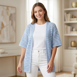 May include: A light blue open-front crochet cardigan featuring a repeating square grid pattern, elbow-length sleeves, and a straight hemline, worn over a plain white t-shirt and white denim pants, creating a layered look with a textured finish.
