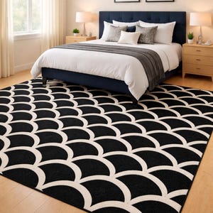 Peut inclure: Une chambre avec un lit bleu marine, une literie blanche et des coussins décoratifs. Un tapis à motifs noir et blanc recouvre le sol. Deux tableaux encadrés sont au-dessus du lit et des tables de chevet avec des lampes sont de chaque côté.