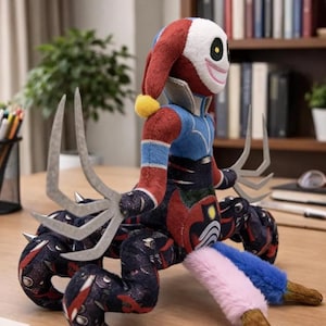May include: A plush toy character with a red and white jester hat, blue and red torso, and a multi-legged base. The toy has a smiling face and metallic claws. The legs are patterned with dark blue and red.