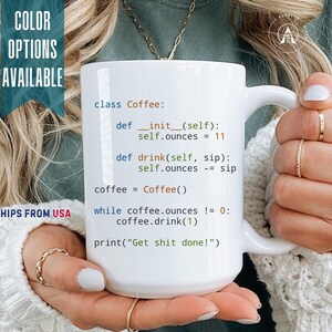 May include: A white ceramic mug featuring black, blue, and orange computer code text that reads: class Coffee: def __init__(self): self.ounces = 11, def drink(self, sip): self.ounces -= sip, coffee = Coffee(), while coffee.ounces != 0: coffee.drink(1), print("Get shit done!")