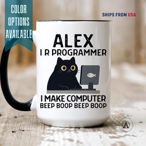 May include: A white ceramic mug with a black handle and interior. The front features a black cat sitting at a computer with a fish icon on the screen. The text reads: ALEX I R PROGRAMMER I MAKE COMPUTER BEEP BOOP BEEP BOOP. The design is centered.