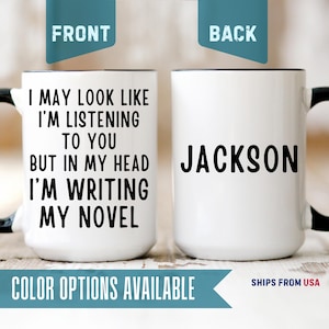 May include: A white ceramic mug with a black handle and interior. The front features the black text: I MAY LOOK LIKE I'M LISTENING TO YOU BUT IN MY HEAD I'M WRITING MY NOVEL. The back displays the name JACKSON in black capital letters.