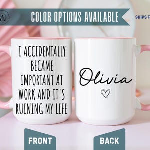 May include: Two white ceramic mugs with pink handles and interiors. The front mug features the black text: I ACCIDENTALLY BECAME IMPORTANT AT WORK AND IT'S RUINING MY LIFE. The back mug displays the name Olivia in black script with a small heart.