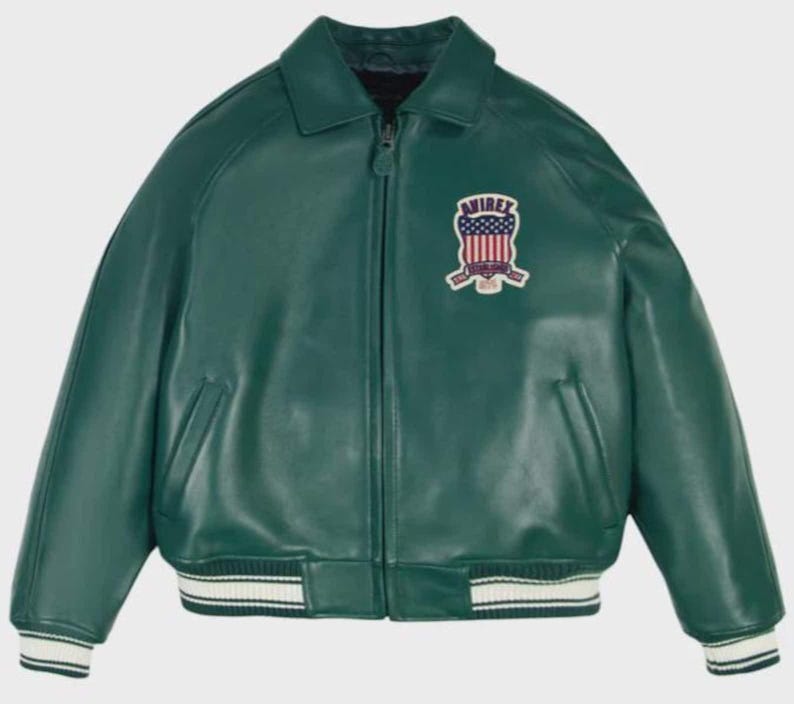 May include: A green leather jacket with a zip-up front, collared neckline, and ribbed cuffs and hem. The jacket features a patch on the chest with the text "AVIREX" and a design incorporating the American flag.