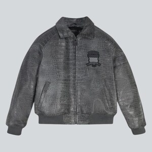 Puede incluir: Chaqueta de cuero gris con textura de cocodrilo. Cuenta con cuello, cierre de cremallera y parche en el pecho. Dobladillo y pu&ntilde;os de canal&eacute;. Prenda de abrigo elegante.
