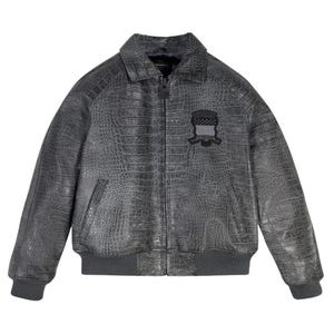 May include: A gray, faux-leather bomber jacket with a crocodile skin texture. The jacket features a collar, a zipper closure, and a small patch on the chest. The cuffs and hem are ribbed.