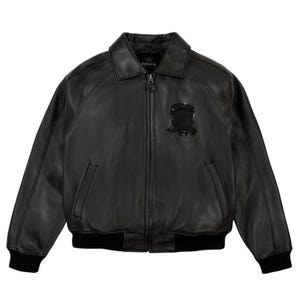Pu&ograve; includere: Giacca bomber in pelle nera con collo, chiusura a zip e un piccolo stemma sul petto. La giacca presenta polsini e orlo a coste. Un capo di abbigliamento esterno classico.