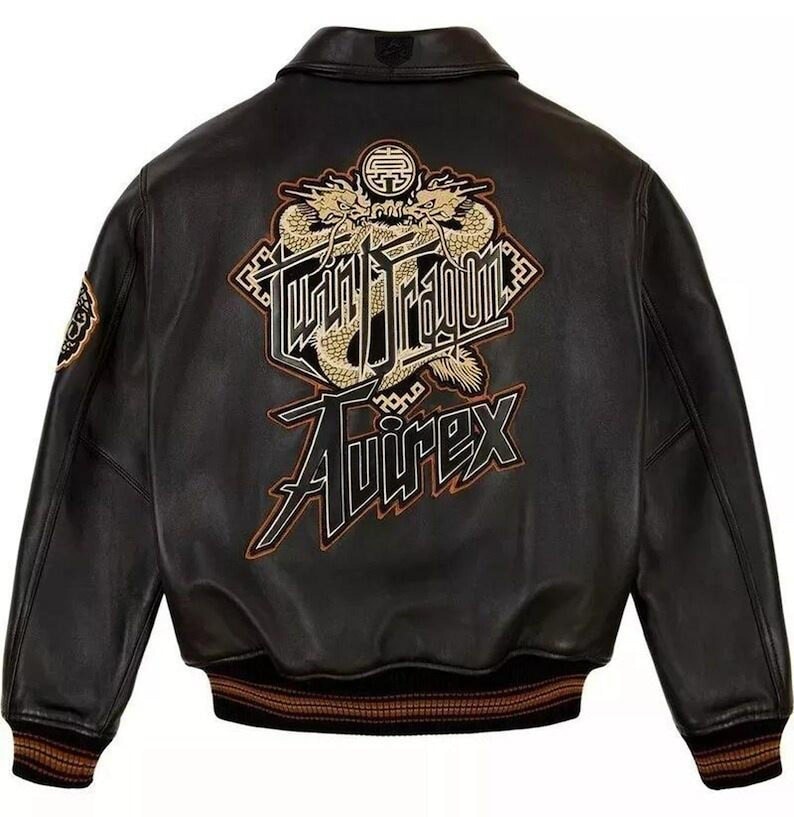 May include: Black leather jacket with a classic bomber silhouette. Features a large embroidered design on the back with a dragon motif and the text "Tokyo Dragon" and "Avirex" in gold and black. The jacket has a ribbed collar and cuffs.