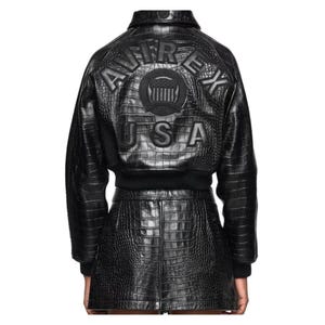 May include: Black leather jacket and skirt set with a crocodile texture. The jacket features the text "AVIREX USA" embossed on the back. The set includes a bomber-style jacket and a mini skirt.