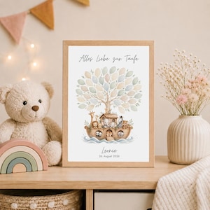 Könnte beinhalten: Ein gerahmter Druck mit einer Aquarellillustration der Arche Noah, die verschiedene Tiere darstellt. Das Kunstwerk enthält einen Baum mit blattförmigen Elementen und den Text "Alles Liebe zur Taufe" sowie den Namen "Leonie" mit einem Datum. Der Rahmen ist hellbraun.