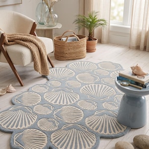 May include: A light blue area rug with a repeating pattern of cream-colored seashell motifs. The rug features a scalloped edge that follows the outline of the shells, creating a textured surface with a soft, tufted appearance throughout the design.