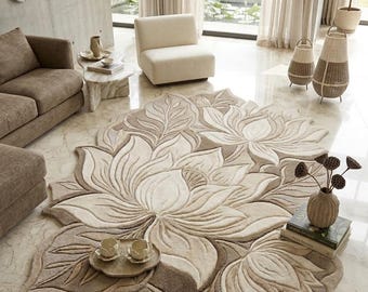 May include: A large, beige floral rug dominates the room, featuring a detailed lotus flower design. The rug is surrounded by neutral-toned furniture, including a sofa, chair, and side table. Decorative elements include a wall sculpture and lamps.