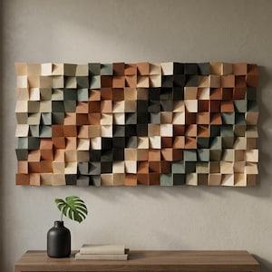 Può includere: Un'opera d'arte murale rettangolare composta da numerosi piccoli blocchi di legno sporgenti in varie tonalità di marrone, beige, nero e verde spento. I blocchi sono disposti a griglia, creando una superficie tridimensionale e strutturata.