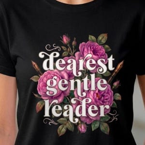 May include: Black t-shirt featuring a floral design with pink roses and green leaves. The text "Dearest Gentle Reader" is written in a decorative font, accompanied by a quill. A stylish and literary-themed apparel.