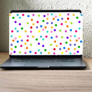 May include: A black laptop displays a white screen covered in colorful polka dots. The dots are in various colors, including red, orange, yellow, green, blue, and purple. The laptop is on a light brown wooden surface.