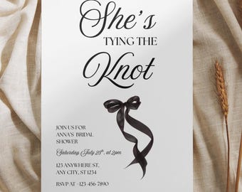 May include: A white rectangular invitation card featuring the black text She's TYING THE Knot, a black ribbon bow illustration, and event details including Anna's bridal shower, Saturday, July 25th at 2pm, 123 Anywhere St, and RSVP 123-456-7890.