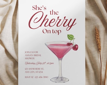 May include: A white rectangular bridal shower invitation card featuring the text She's the Cherry On top, with a watercolor illustration of a pink cocktail in a martini glass garnished with two red cherries on a green stem and event details.