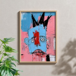 May include: A framed wall art print featuring a stylized, expressive portrait with a light blue face, a bold red vertical stripe across the nose, and a jagged black crown shape on top. The background consists of layered pink and blue paint strokes.