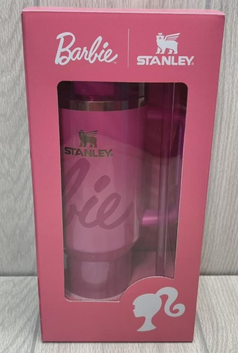 Op de afbeelding: Een roze Barbie- en Stanley-geschenkset. De doos heeft het Barbie-logo en een silhouet van Barbie. Het Stanley-logo is ook zichtbaar. De set bevat een roze beker met het woord "Barbie" erop.