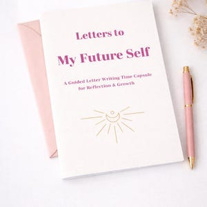 Könnte beinhalten: Ein weißes Notizbuch mit dem Titel "Letters to My Future Self" mit einem rosa Stift und Umschlag. Das Notizbuch hat goldene Akzente und den Text "A Guided Letter Writing Time Capsule for Reflection & Growth."