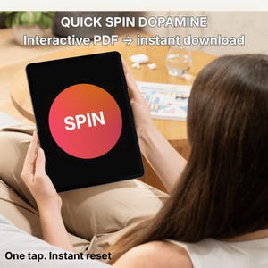 Peut inclure: Une tablette noire affiche un cercle rouge et orange avec le mot blanc "SPIN". Le texte au-dessus indique "QUICK SPIN DOPAMINE" et "Interactive PDF -> téléchargement instantané". En dessous, le texte dit "Un clic. Réinitialisation instantanée".