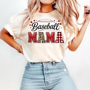 May include: Cream-colored t-shirt with the words "Baseball MAMA" in a baseball-themed design. The word "Baseball" is in black script, and "MAMA" features leopard print and red plaid patterns.