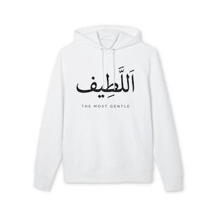 Puede incluir: Sudadera con capucha blanca con bolsillo delantero y cordón. La caligrafía árabe negra dice "Al-Latif" con la traducción al inglés "The Most Gentle" debajo. Una prenda informal y cómoda.