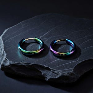 Può includere: Un paio di orecchini a cerchio circolari con una finitura metallica iridescente color arcobaleno. Ogni cerchio presenta una superficie liscia e lucida con un piccolo dettaglio circolare trasparente incastonato nella banda metallica.