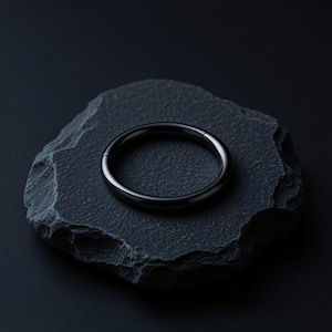 May include: A polished black metal hoop ring with a seamless hinged closure mechanism. The circular jewellery piece features a smooth, reflective surface and a consistent thickness throughout its entire circumference, presenting a clean and simple design.