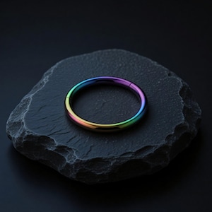 Può includere: Un anello circolare con una finitura liscia e lucida caratterizzato da una vibrante sfumatura arcobaleno che passa attraverso tonalità di viola, blu, verde, giallo e arancione. L'anello è dotato di un meccanismo di chiusura a cerniera.