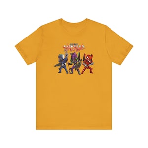 May include: Mustard yellow t-shirt featuring a graphic of three stylized figures in blue, purple, and red armor, with weapons. The text "EVANGELION" is above the figures in red and white. The shirt is made of a soft material.