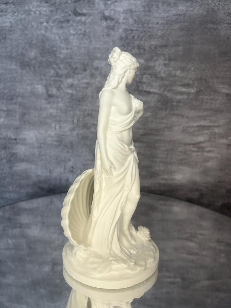 Side profile view
Side profile of Venus / Aphrodite statue showing flowing drapery details and feminine silhouette. Greek mythology inspired goddess sculpture for altar decor, spiritual home decor, mythology lovers gift, aesthetic white figurine, divine feminine decor, shell symbolism statue, minimalist mythology art, decorative PLA sculpture.