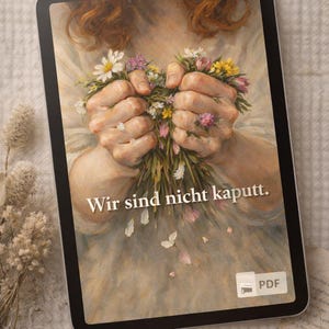 Könnte beinhalten: Ein digitales Tablet zeigt ein Gemälde von Händen, die einen Strauß weißer, rosa und gelber Blumen halten. Der Text "Wir sind nicht kaputt" ist sichtbar. Ein PDF-Symbol befindet sich in der Ecke. Das Tablet liegt auf einer strukturierten Oberfläche.