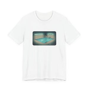 May include: White t-shirt featuring a rectangular graphic of a swimming pool with teal water and a diving board. The graphic has a retro, vintage aesthetic. The words "POOL AREA" are visible in the graphic.