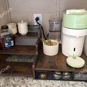 May include: A white ceramic mug with a black handle and the text "But First, Coffee" in a handwritten style. The mug is on a white surface. The mug is approximately 4 inches tall.