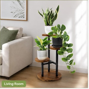 May include: A three-tiered plant stand with a dark wood finish and black metal supports. The stand holds three potted plants with green foliage. The base of the stand has the text "Living Room".
