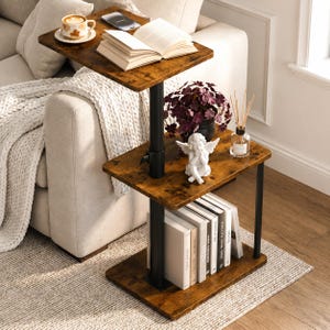 May include: A three-tier side table with a dark brown wood grain finish and a black metal frame. The top tier holds a coffee cup, a smartphone, and an open book. The middle tier features a small plant, a white angel figurine, and a reed diffuser.