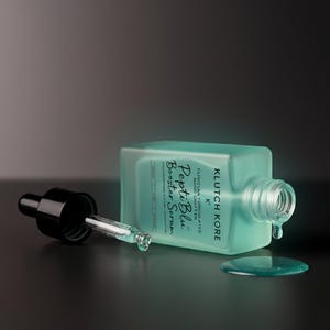 Puede incluir: Una botella turquesa de Pepti Blue Booster Serum con un cuentagotas negro y un peque&ntilde;o charco de suero. La botella est&aacute; tumbada de lado, con el cuentagotas separado. El texto "Pepti Blue Booster Serum" es visible.
