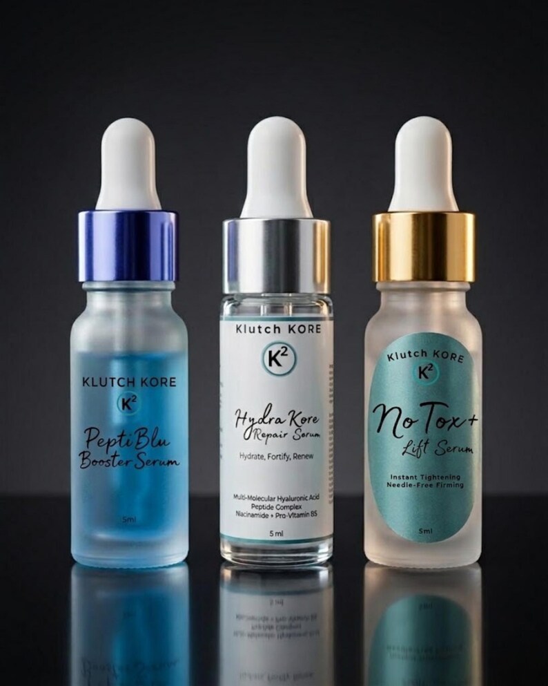 May include: Three glass serum bottles with white droppers. The bottles have blue, silver, and gold accents. Each bottle has the "Klutch Kore" logo and product names: "Pepti Blu Booster Serum", "Hydra Kore Repair Serum", and "No Tox+ Lift Serum".